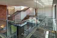 Hangend tussenverdieping met stalen constructie, glazen paneelvloer en volledig glazen balustrade met rvs handregel