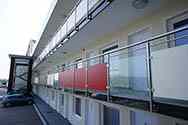 Balkonhek van balustrade met rvs staanders en leuningen. Balustradevulling van veiligheidsglas en HPL (hogedruk kunststofplaat) panelen