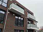 Glazen balustrade met rond hoog gepolijst rvs leuningen