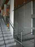 Glazen balustrade met rond hoog gepolijst rvs leuning op trappen.