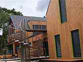 Stalen trap met RVS draagconstructie en houten treden. RVS balustrade met knieregels