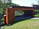 Ingang van het huis en een erker bekleed met Corten staalplaten gemonteerd op een stalen structuur