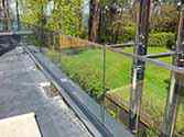 Volledig glazen balustrade met rvs handregel gemonteerd met aluminium vloerprofilel op het terras