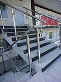 Hoog gepolijst rvs staanders en leuningen. Balustradevulling van gehard glaspanelen.
