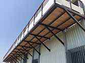 Balkon met stalen constructies, houten vloerdelen en balustrades met glazen vulling.